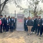 Law students at a free legal aid outreach camp banner reading "School of Law Free Legal Aid" in rural Maharashtra