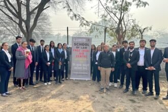 Law students at a free legal aid outreach camp banner reading "School of Law Free Legal Aid" in rural Maharashtra
