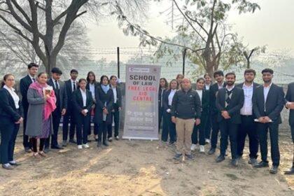 Law students at a free legal aid outreach camp banner reading "School of Law Free Legal Aid" in rural Maharashtra