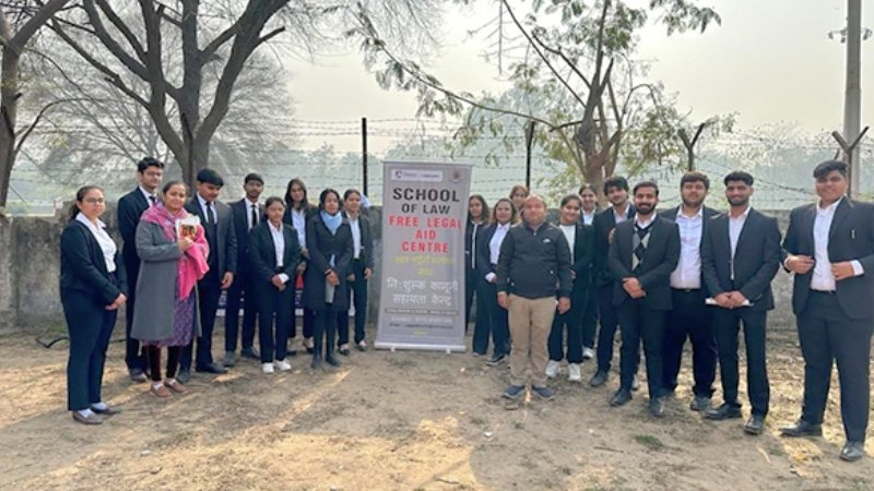 Law students at a free legal aid outreach camp banner reading "School of Law Free Legal Aid" in rural Maharashtra