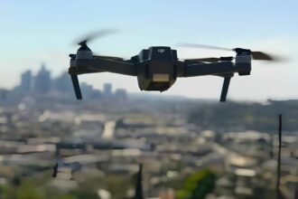 Black quadcopter drone flying against a hazy blue sky over Pune