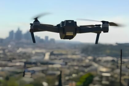 Black quadcopter drone flying against a hazy blue sky over Pune