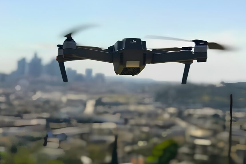 Black quadcopter drone flying against a hazy blue sky over Pune