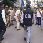 CBI officials flanked by police personnel during a raid at a barricaded street in the NEET-UG paper leak probe