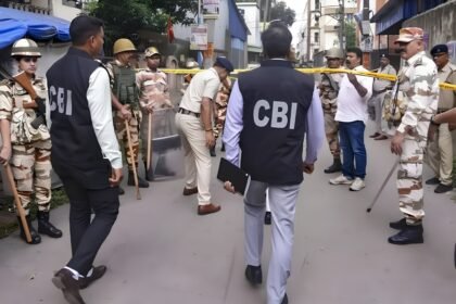 CBI officials flanked by police personnel during a raid at a barricaded street in the NEET-UG paper leak probe