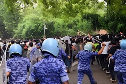 Riot police in helmets and blue camouflage uniforms facing a crowd of protesters during the July 20 Jantar Mantar demonstration