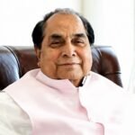 Portrait of Dr. D. Y. Patil, an elderly man in white traditional attire, seated in a maroon armchair