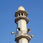 Loudspeakers mounted on a minaret tower against a blue sky
