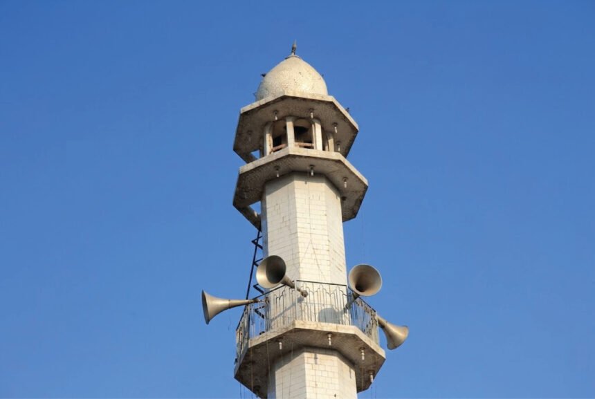 Loudspeakers mounted on a minaret tower against a blue sky