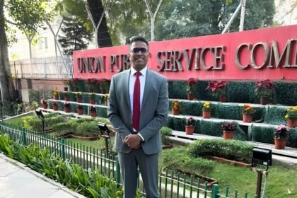 Adv. Sunil Kadam in a suit standing in front of the Union Public Service Commission building sign