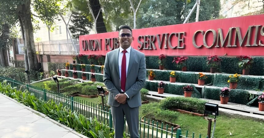 Adv. Sunil Kadam in a suit standing in front of the Union Public Service Commission building sign