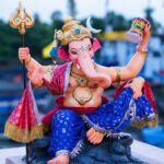 सजवलेल्या गणेशमूर्तीच्या मुखाचे क्लोजअप छायाचित्र, उत्सवी पार्श्वभूमी
