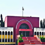 Maroon-colored Bombay High Court building facade with an Indian flag on the roof