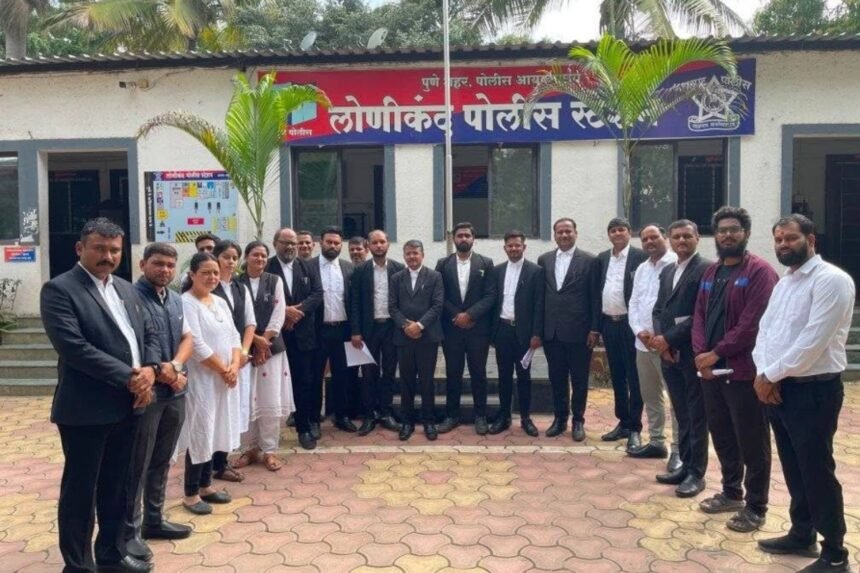Group of lawyers in black coats standing in front of the Lonikand Police Station