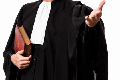 काळ्या वकिली झग्यातील व्यक्ती पुस्तके हातात धरून हावभाव करताना