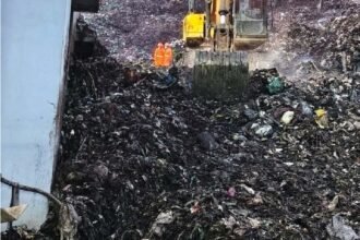 मोशी कचरा डेपोच्या ढिगाऱ्यात बचावकार्य सुरू असताना उत्खनन यंत्र व नारिंगी सुरक्षा जॅकेटमधील कामगार