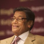 के. के. वेणुगोपाल यांचे स्मितहास्य करतानाचे छायाचित्र, चष्मा व सूट परिधान केलेले