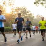 सकाळच्या उन्हात रस्त्यावर धावणाऱ्या धावपटूंचा समूह