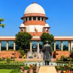 भारताच्या सर्वोच्च न्यायालयाची इमारत, पांढरा घुमट आणि लाल दगडी बांधकाम, वर तिरंगा ध्वज, निरभ्र निळ्या आकाशाच्या पार्श्वभूमीवर