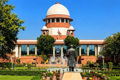 भारताच्या सर्वोच्च न्यायालयाची इमारत, पांढरा घुमट आणि लाल दगडी बांधकाम, वर तिरंगा ध्वज, निरभ्र निळ्या आकाशाच्या पार्श्वभूमीवर